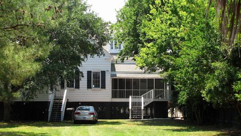 White clapboard house raised on a high foundation with outside stairs and a screened porch
